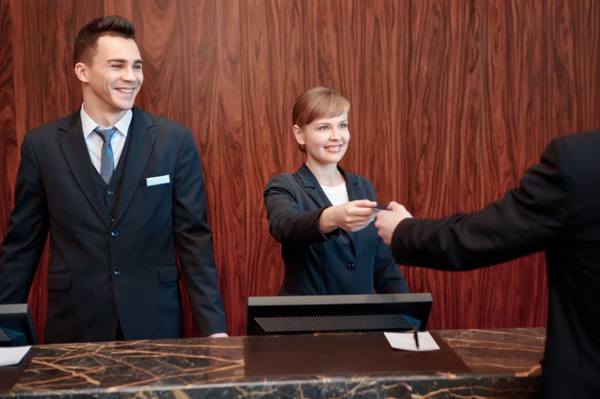 female and a male receptionist welcoming guest and giving the room key