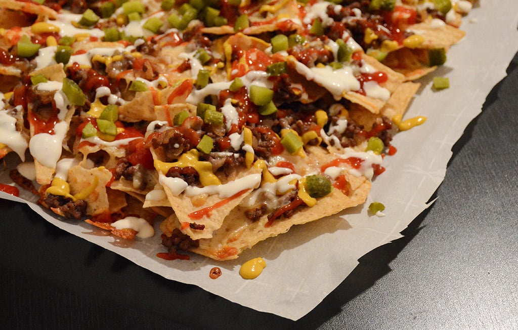 nachos with cheeseburger toppings on parchment paper