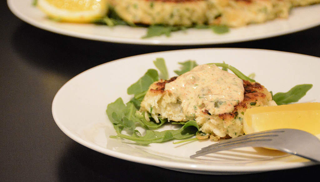 one crab cake with remoulade missing a bite