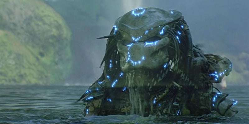The Predator slowly rises out of a lake, with blue lights all over him