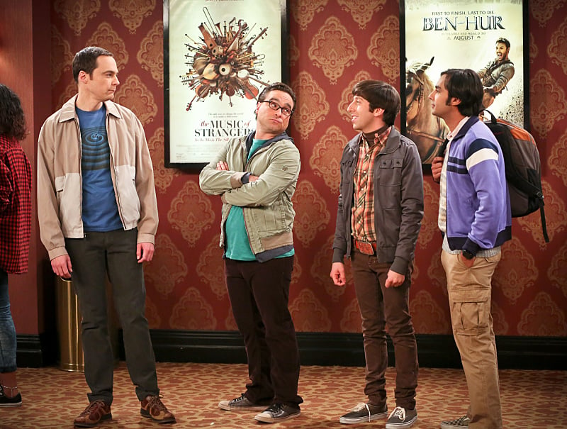 Jim Parsons, Johnny Galecki, Simon Helberg, and Kunal Nayyar stand in line in a scene from CBS's The Big Bang Theory