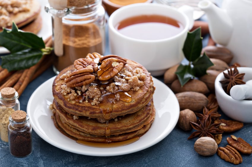 stack of spiced pancakes with brown sugar, syrup, and pecans