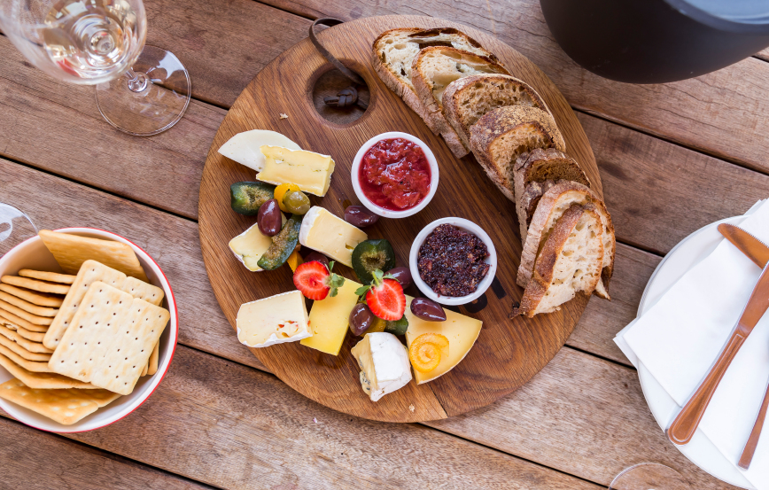 overhead image of a gourmet cheese platter served with bread and wine