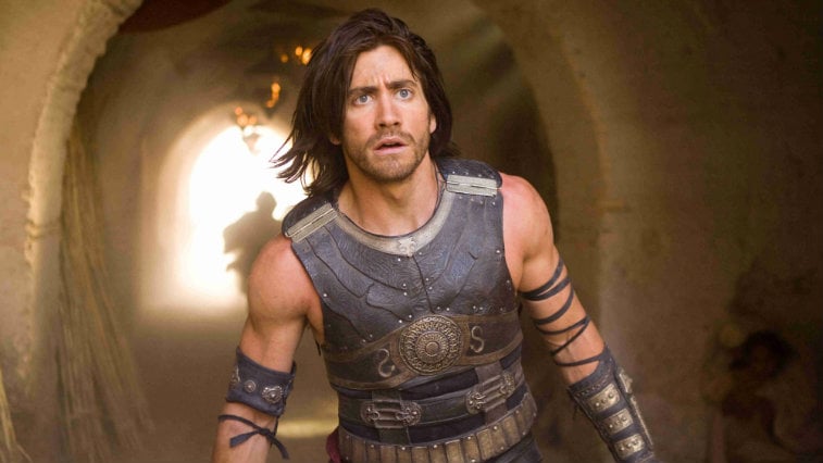 Jake Gyllenhaal looking ahead surprised in front of a tunnel wearing armor in Prince of Persia The Sands of Time