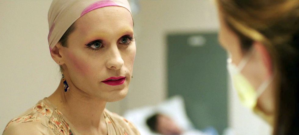 Jared Leto with full makeup, wearing a bald cap and a white dress