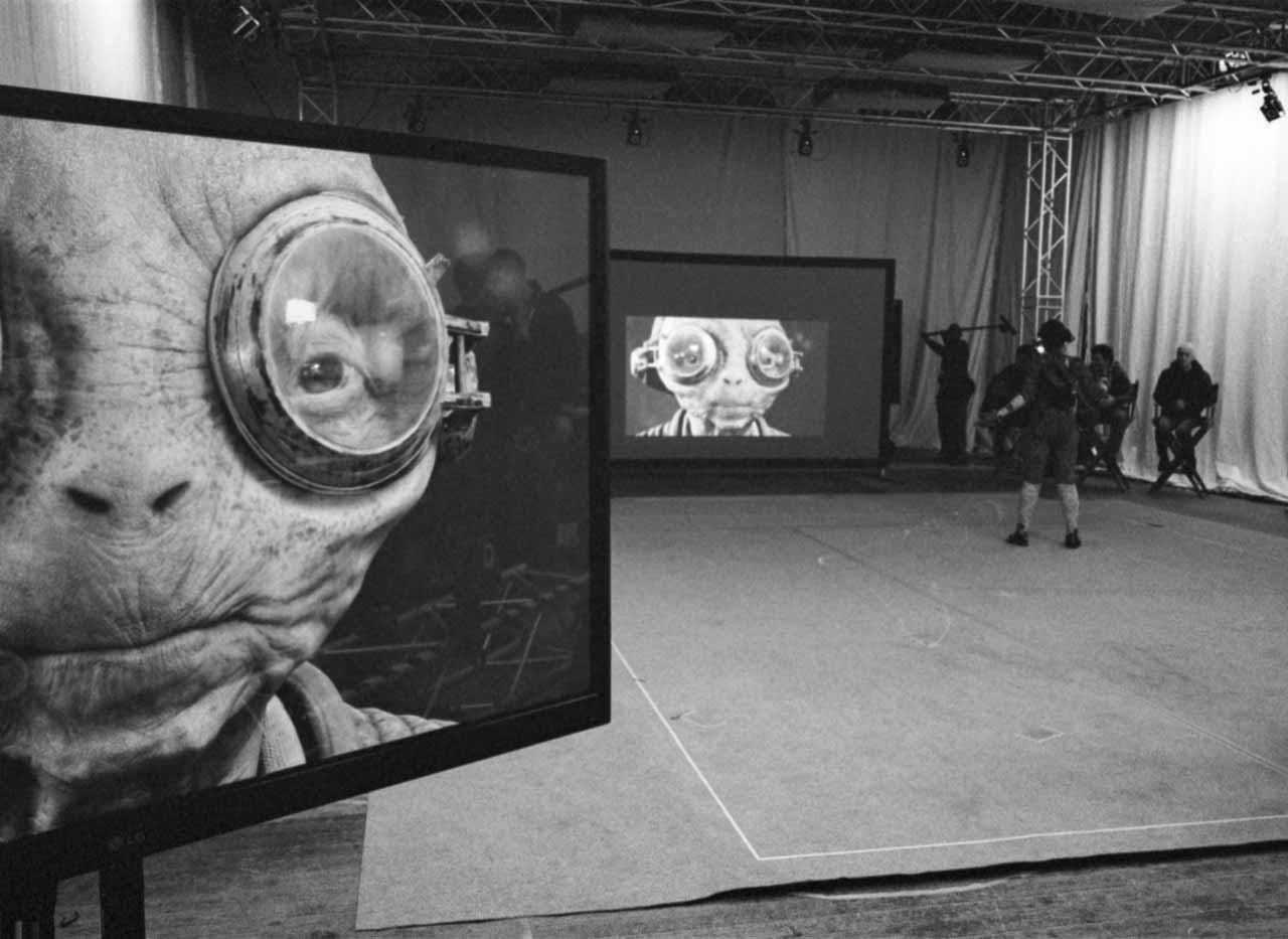 Maz Kanata on a pair of large screens in an otherwise empty studio