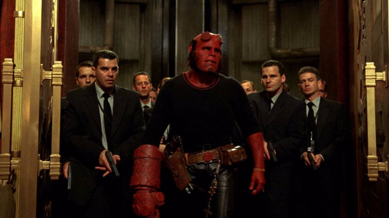 Ron Perlman in Hellboy II The Golden Army is standing in front of a group of men in suits.