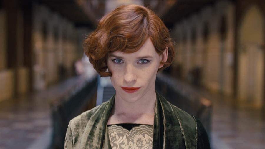 Eddie Redmayne dressed as a woman, wearing a green dress, and donning red lipstick