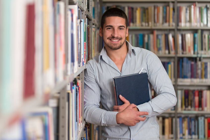Smiling student holding a book in library