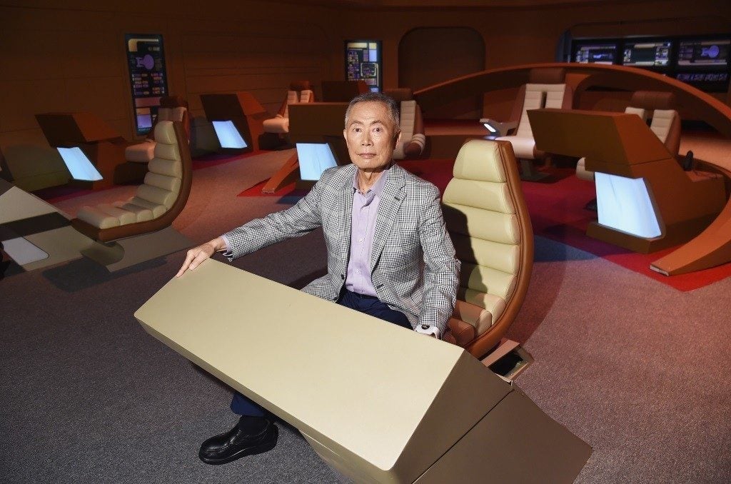 Actor George Takei at a desk on the set of Star Trek