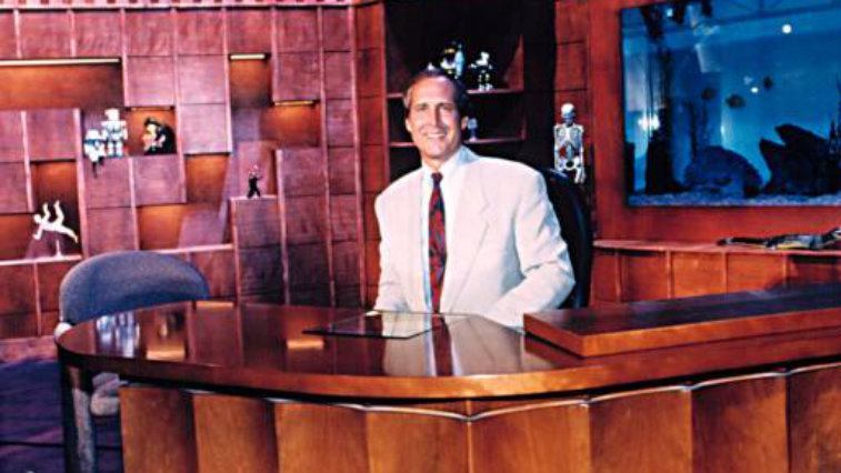 Host Chevy Chase at his desk on The Chevy Chase Show