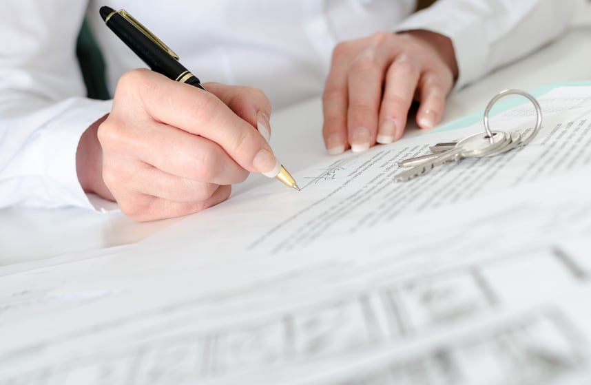 woman signing paperwork to buy a home