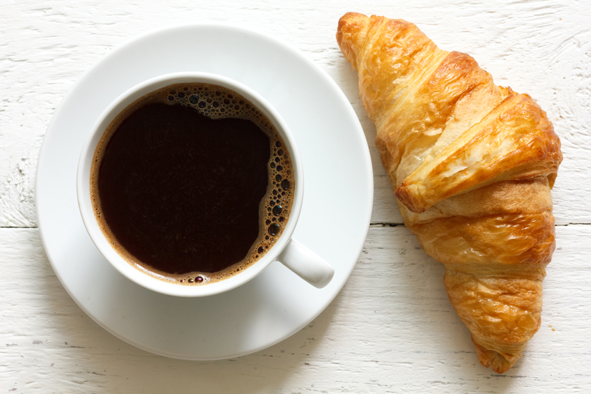 Croissant and coffee on wooden background