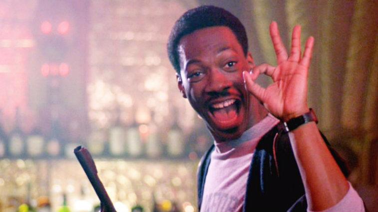 Eddie Murphy smiling in Beverly Hills Cop and giving the a-ok sign
