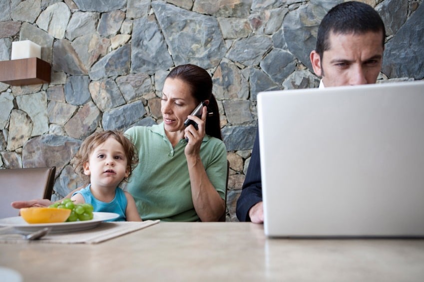mother and father working at the breakfast table with their son