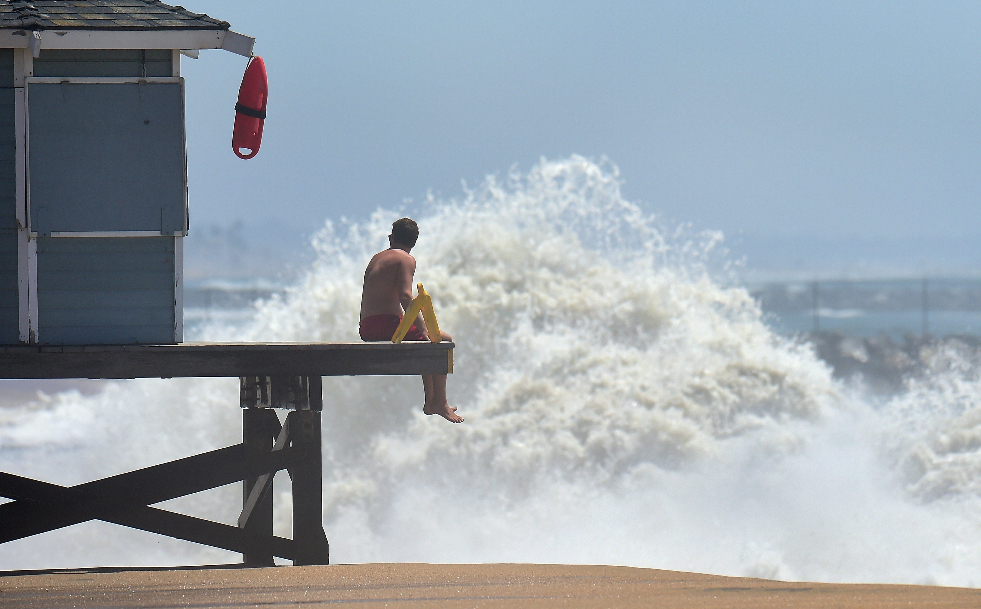 A lifeguard keeps a lookout as big waves crash ashore at Seal Beach, California | Frederic J. Brown/Getty Images