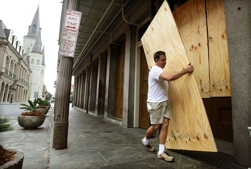 A man boards up a New Orleans store front