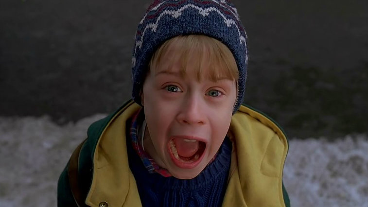 Young Macaulay Culkin screams while wearing a hat and a coat in Home Alone 2