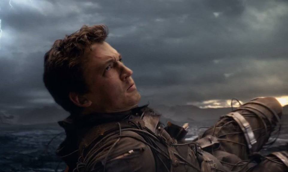 Miles Teller in Fantastic Four, laying on the ground and looking defiantly up to the right of the frame