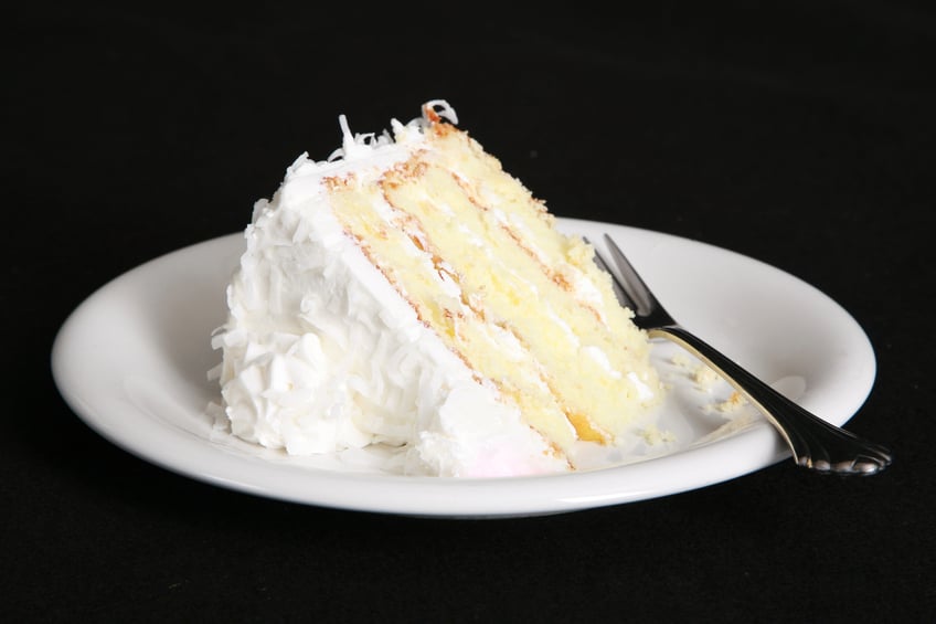 Slice of coconut cake with fork in a plate