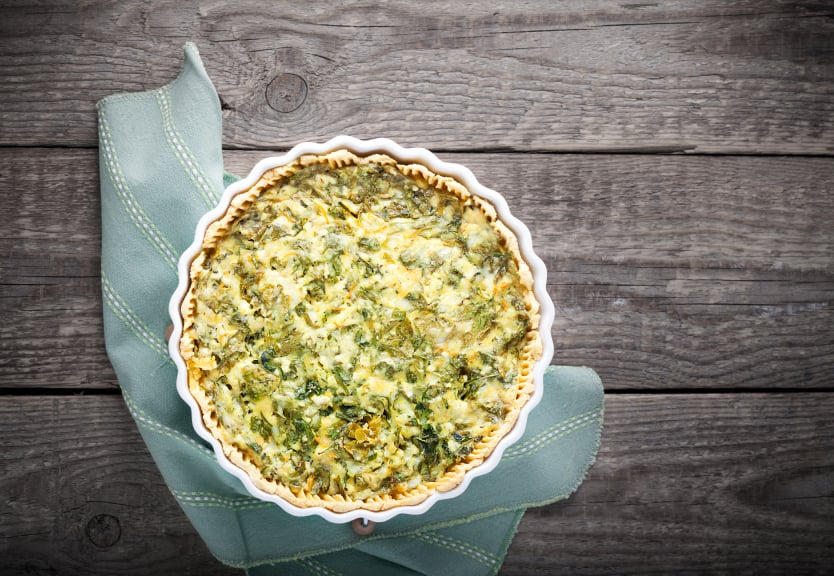 overhead shot of a spinach quiche on a wooden table