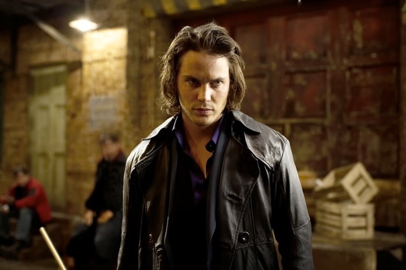 Taylor Kitsch as Gambit, wearing a leather jacket, and holding a pool cue, looking angrily off to the right of the frame