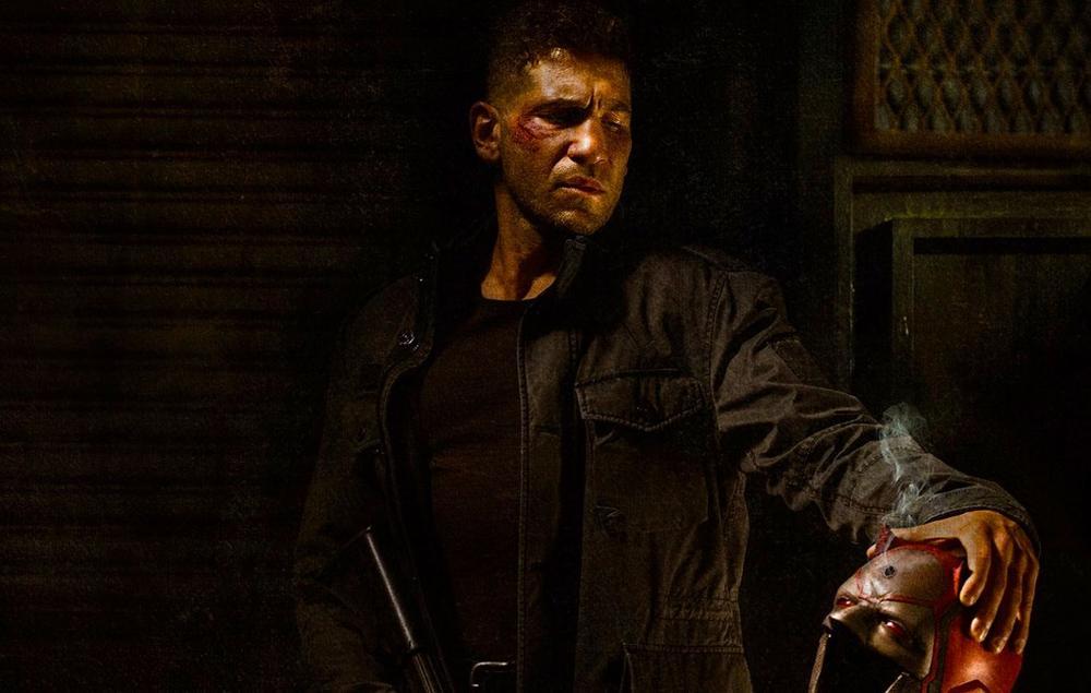 Actor Jon Bernthal looking down and holding a mask in The Punisher on Netflix