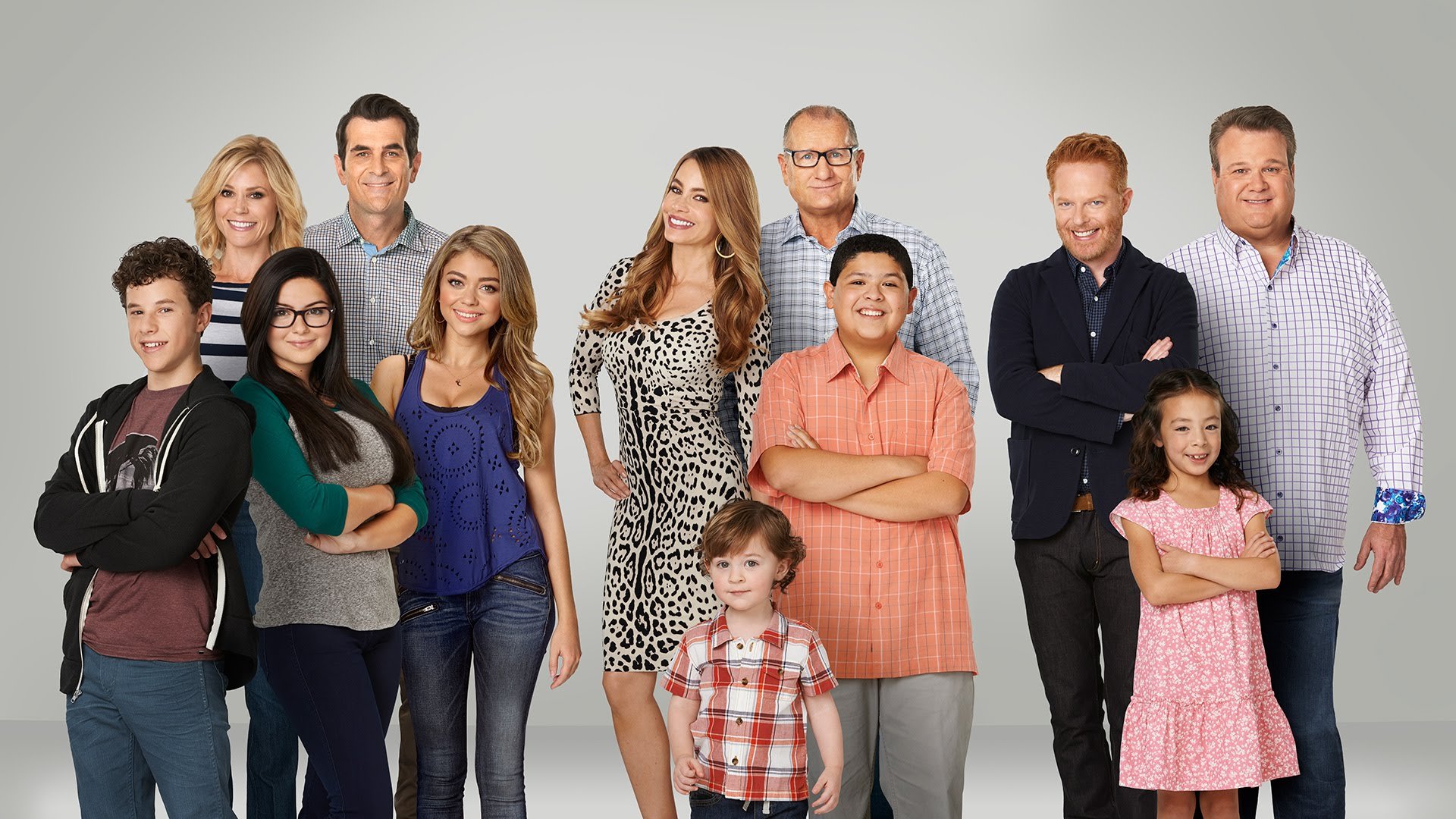 The cast of Modern Family stand in front of a white background 
