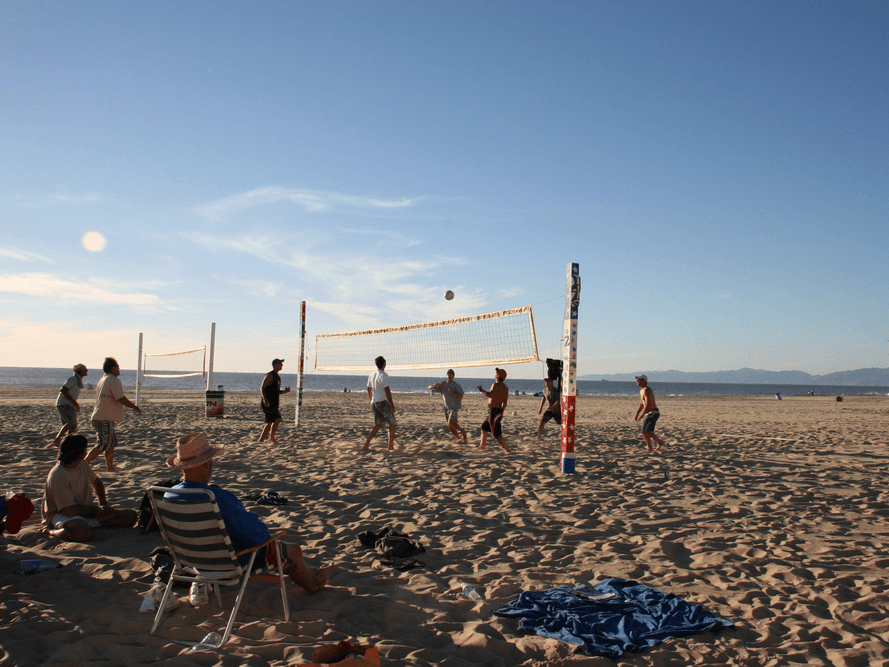 Beachgoers play volleyball on a California beach