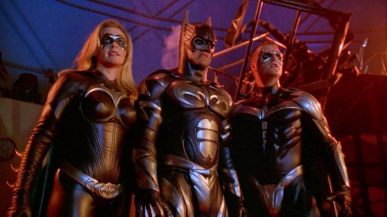 the cast of Batman and Robin stand in their bat suits