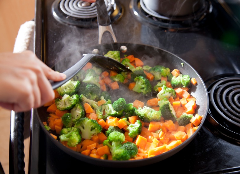 cooking sweet potatoes and broccoli in a skillet