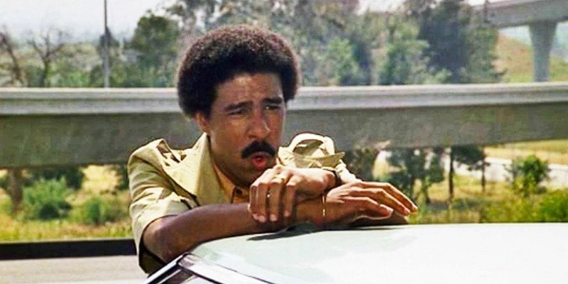 richard pryor in Silver Streak standing behind a car and making a face