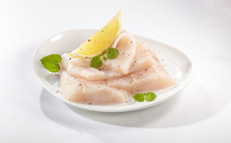 white fish in a white plate with lemon slice
