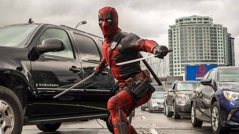 Ryan Reynolds in Deadpool standing with his weapons in a traffic jam
