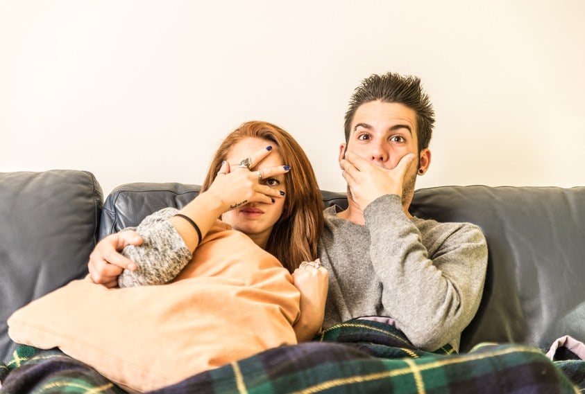 Couple watching horror movie on television on the couch