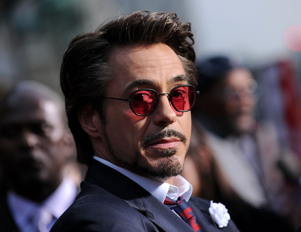 Rober Downey Jr. in red sunglasses, and a dapper blue suit with a red tie
