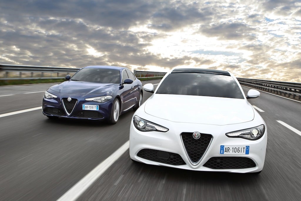 Two 2017 Alfa Romeo Giulias racing down the highway.