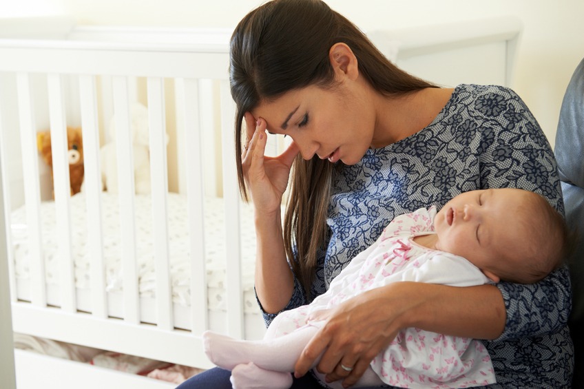 A tired mother handles her baby