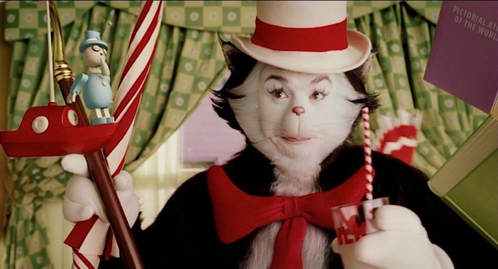 Mike Myers as the Cat in the Hat holding a toy boat on a hook and a cup with a straw