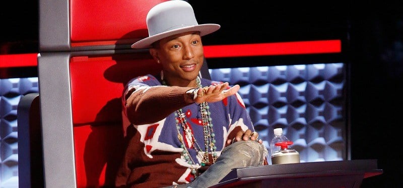 Pharrell with his hand up as if to push the button on The Voice