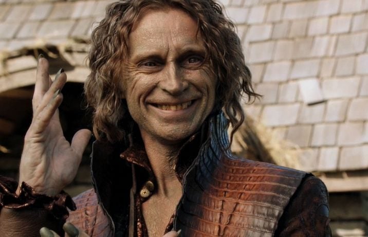 Robert Carlyle as Rumplestiltskin smiling with his hand in the air on Once Upon a Time