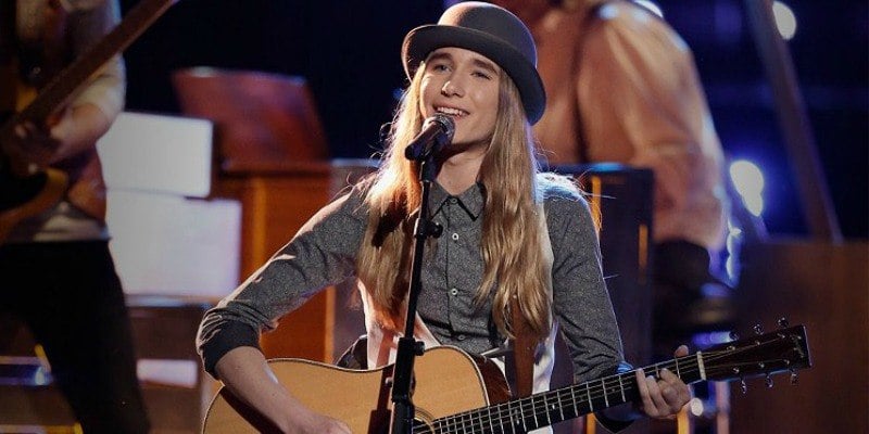 Sawyer Fredercks is singing on stage and playing his guitar on The Voice.