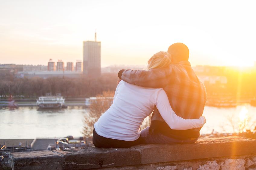 Rear view of a loving couple sitting on a rampart