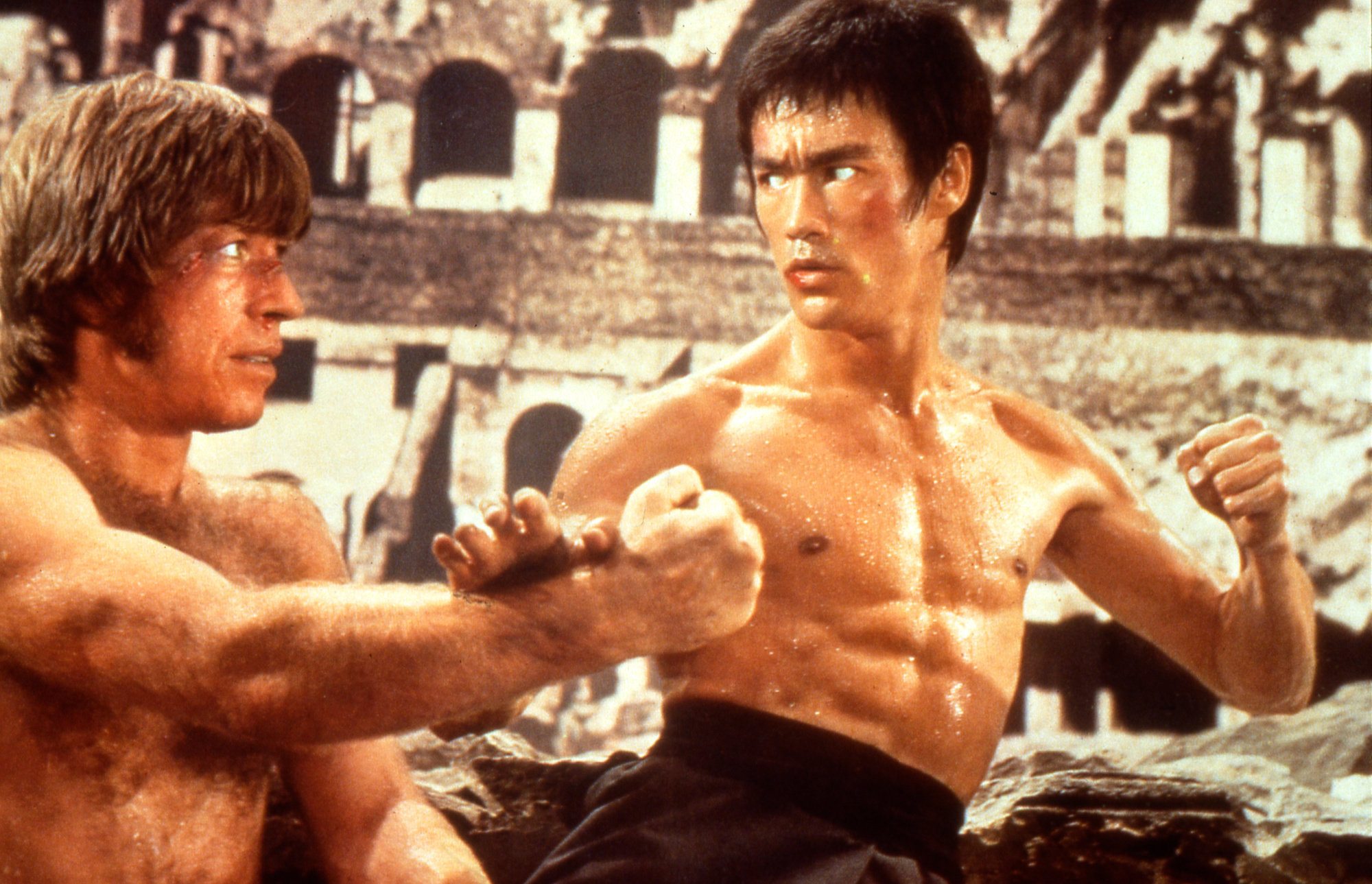 Chuck Norris and Bruce Lee fighting each other in the Roman Colosseum