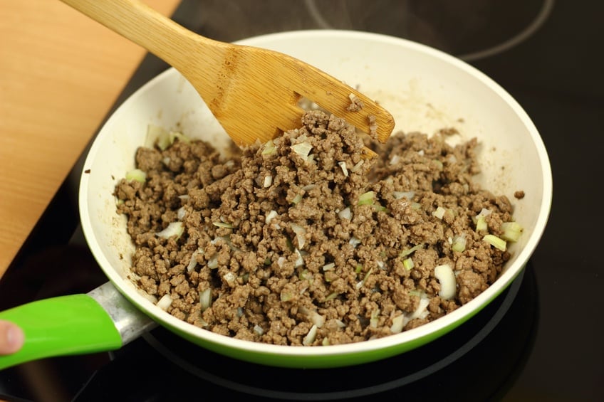 Ground beef cooking in a skillet with onions