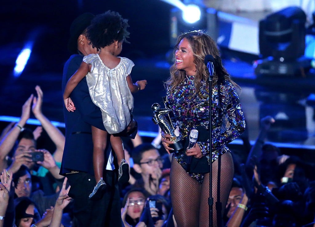Beyoncé holds up an award and smiles at her daughter and husband while at the 2014 VMAs