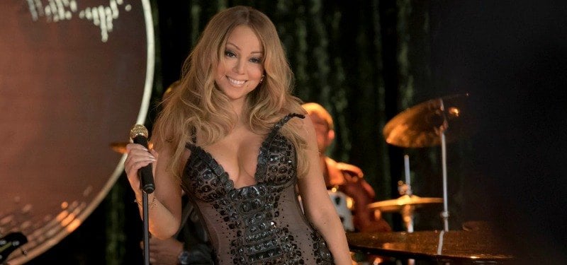 Mariah Carey is smiling in a black body suit.