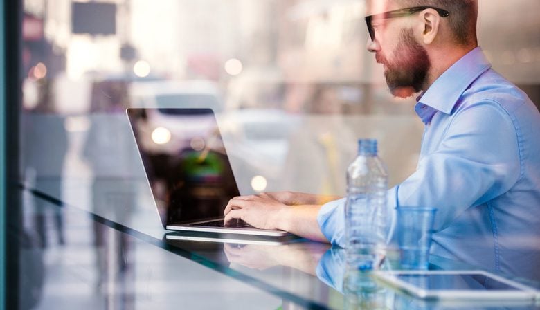 manager sitting in cafe working on laptop