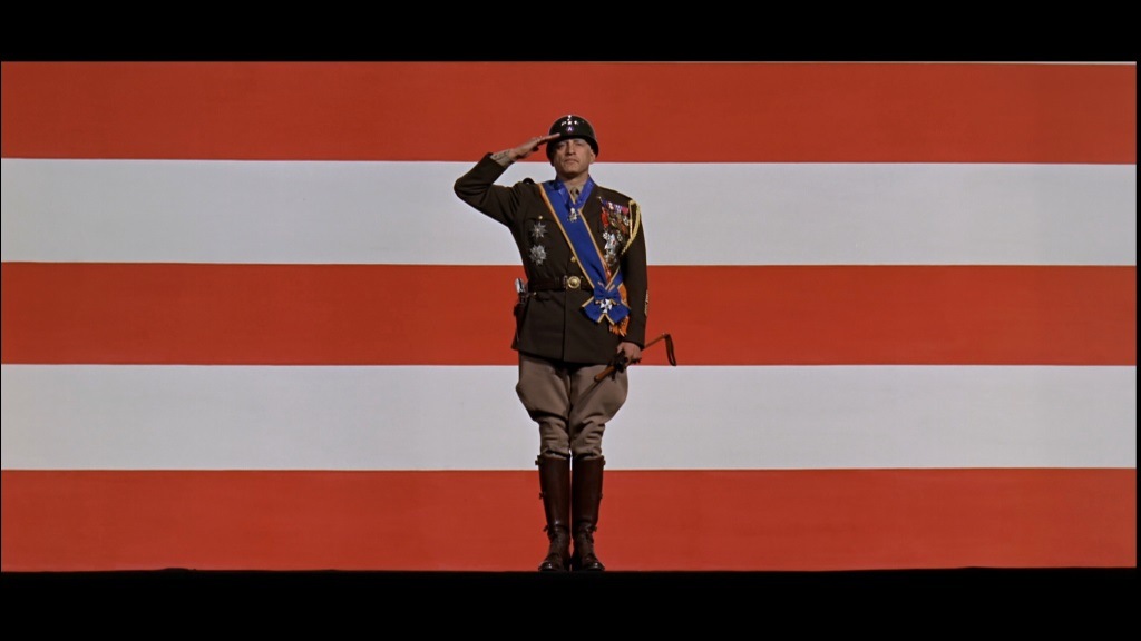 General Patton in uniform saluting in front of an orange and white striped background