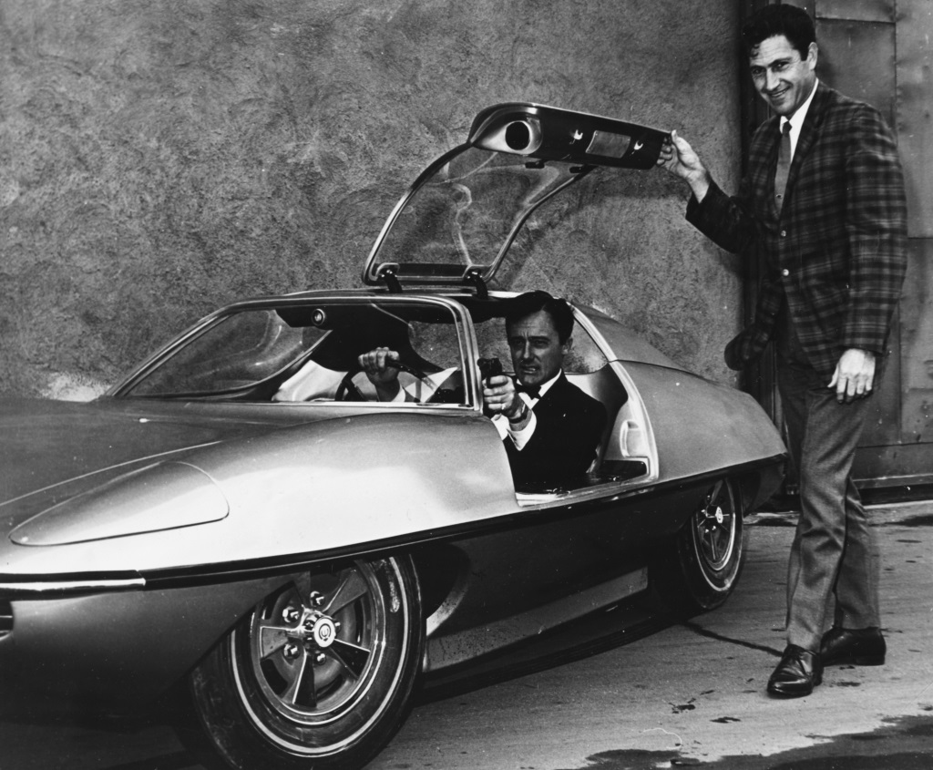 Portrait of actor Robert Vaughn sitting in the new car designed for his television show 'The Man From UNCLE', with the cars designer Gene Winfield